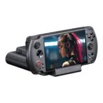 Een zwarte GPD WIN 5 handheld console is te zien in het bijbehorende zwarte oplaad/datadock, schuin naar voren gericht tegen een witte achtergrond. Op het scherm van de console is een close-up te zien van een vrouw met roze haar en cybernetische verbeteringen. De knoppen van het apparaat en de vier LED-lampjes in het dock zijn duidelijk zichtbaar.
