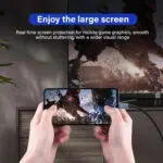 Ein Lifestyle-Bild mit dem Titel "Genießen Sie den großen Bildschirm" zeigt eine Person, die ein Smartphone waagerecht hält, während sie ein actionreiches Videospiel spielt. Das Telefon ist über ein USB-C-Kabel mit einem großen Fernseher im Hintergrund verbunden, der die gleiche Spielgrafik wiedergibt. Der Text beschreibt "Echtzeit-Bildschirmprojektion für mobile Spielgrafiken, flüssig ohne Stottern, mit einer größeren visuellen Reichweite".
